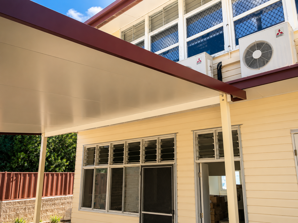 Cream skillion carport attached to Queenslander-style home showing fascia and beam connection detail, custom carport by Shedex Fleurieu SA