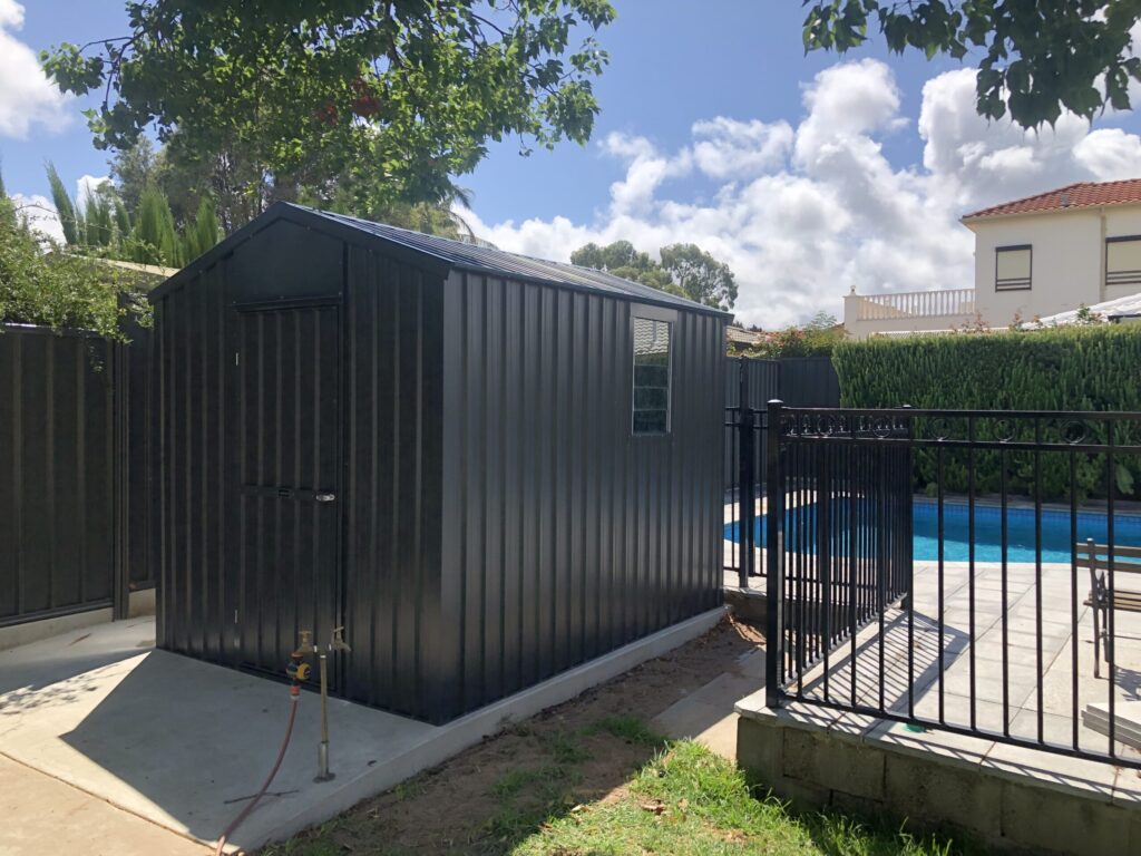 Charcoal colorbond garden shed installed in a residential backyard next to a swimming pool, supplied by Shedex Fleurieu
